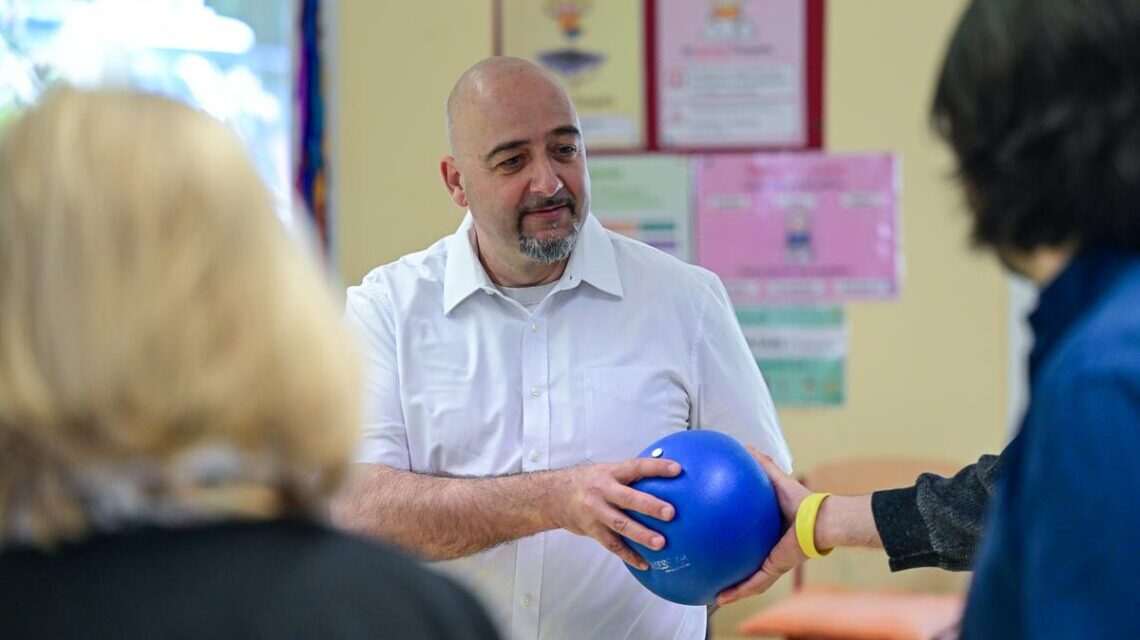 Person reicht einen blauen Ball weiter.