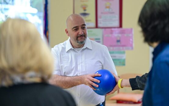 Person reicht einen blauen Ball weiter.